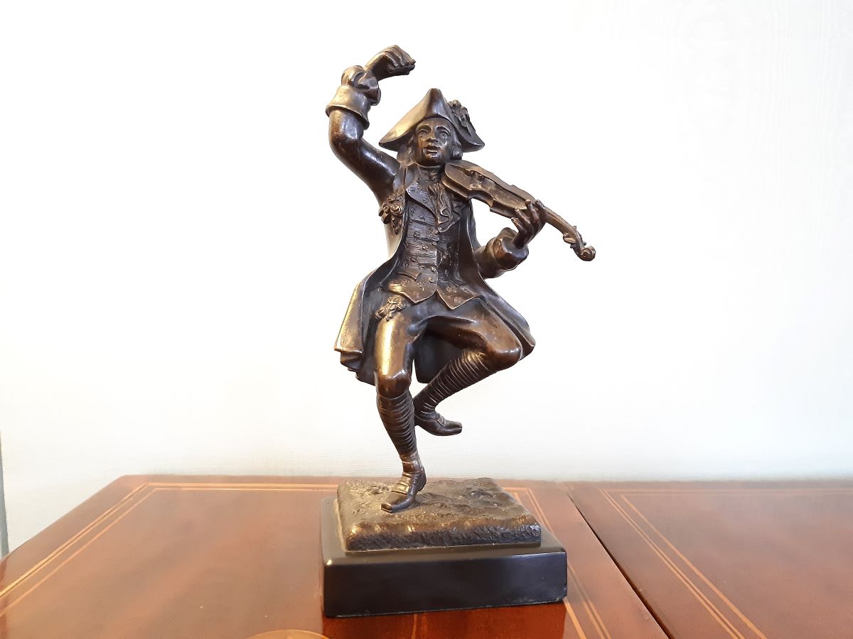 Patinated bronze sculpture of man playing a violin on black marble plinth